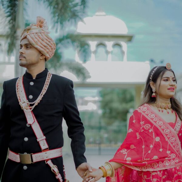 Rajasthani couple dress in traditional attire, posing elegantly against a backdrop of intricate architectural details.