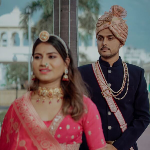 Rajasthani couple dress in traditional attire, posing elegantly against a backdrop of intricate architectural details.