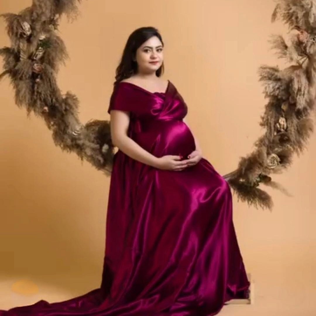 Pregnant woman in off-shoulder burgundy satin maternity gown for photoshoot rental in Udaipur