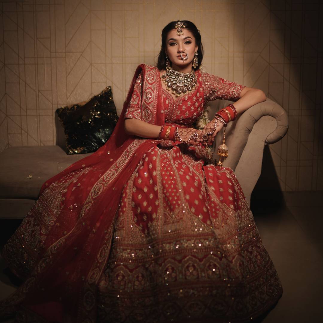 Bride wearing Raw Silk Hand Work Red Lehenga on Rent with intricate embroidery and traditional jewellery.