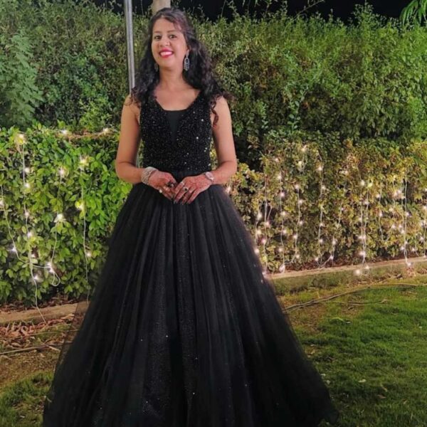 Woman in a fancy black gown on rent posing at an evening party