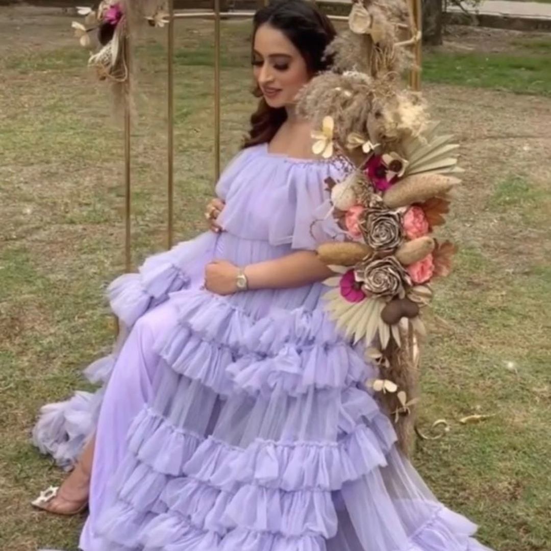Pregnant woman in lavender frill maternity gown sitting on a swing