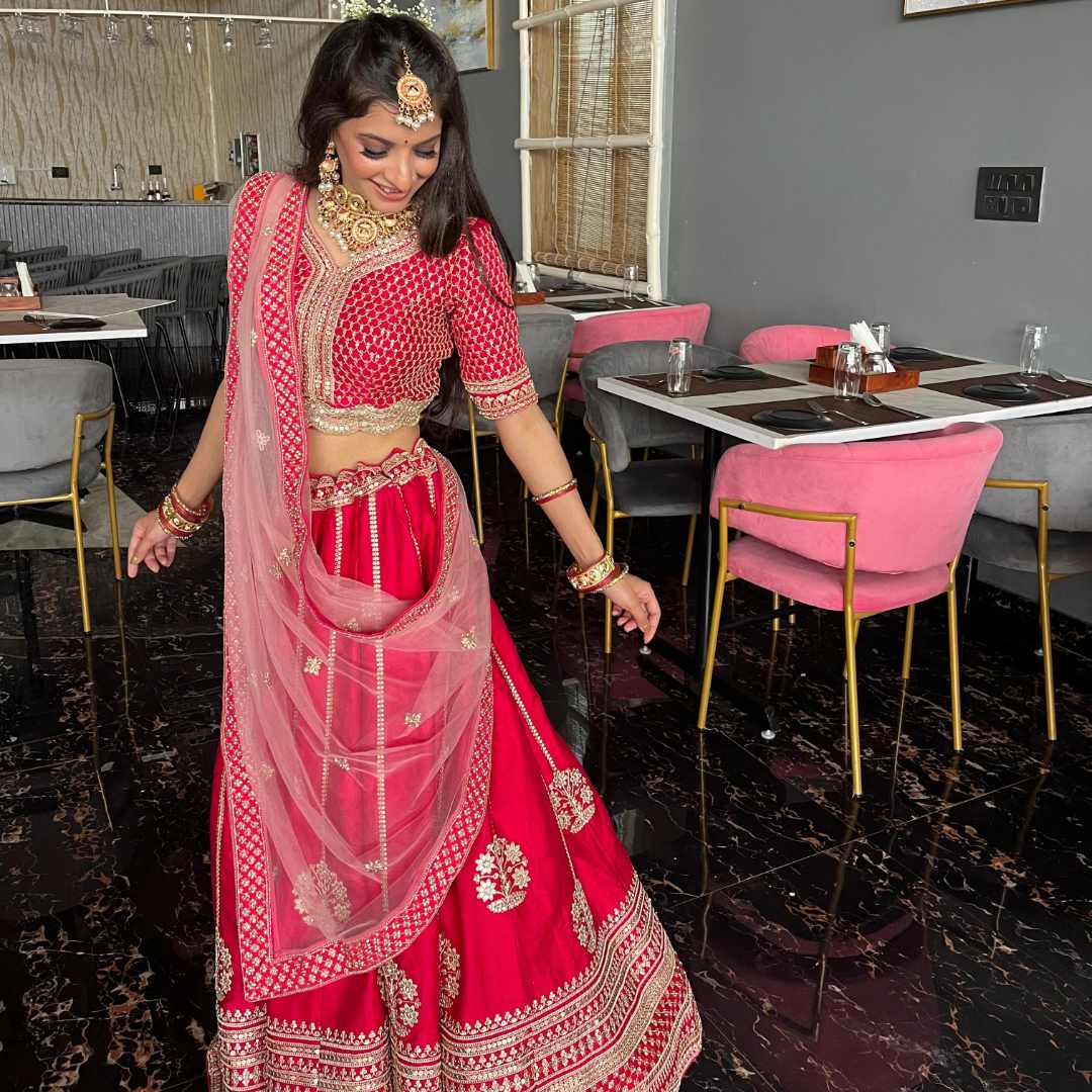 Bride twirling in Designer Red Gota Patti Lehenga with traditional jewelry.