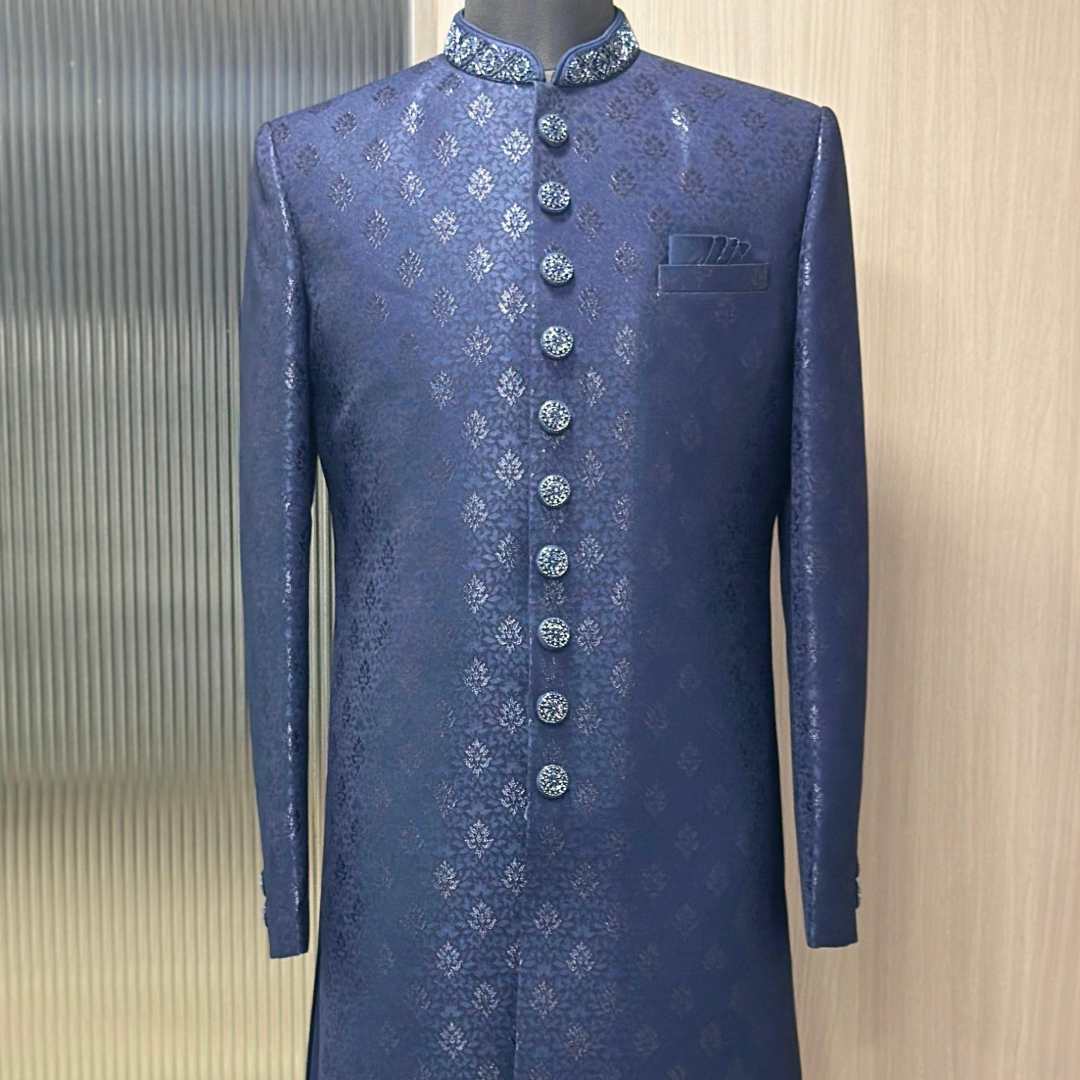 Model wearing Fancyano Navy Blue Printed Achkan for Men, available for rent, featuring subtle blue print and embellished collar.