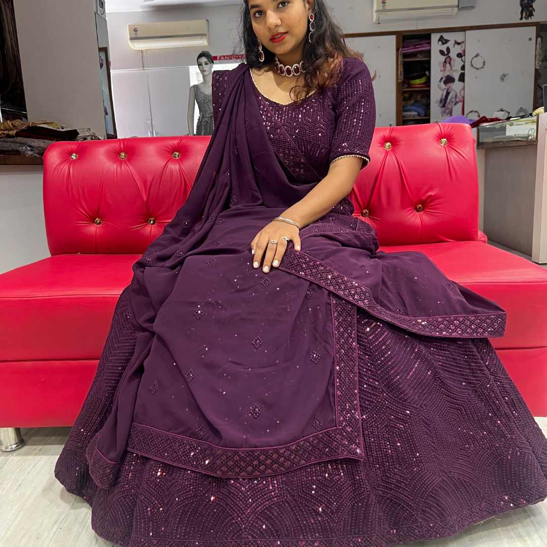 Beautiful woman in Elegant Purple Sider Lehenga on Rent sitting on a red couch at Fancyano, Udaipur.